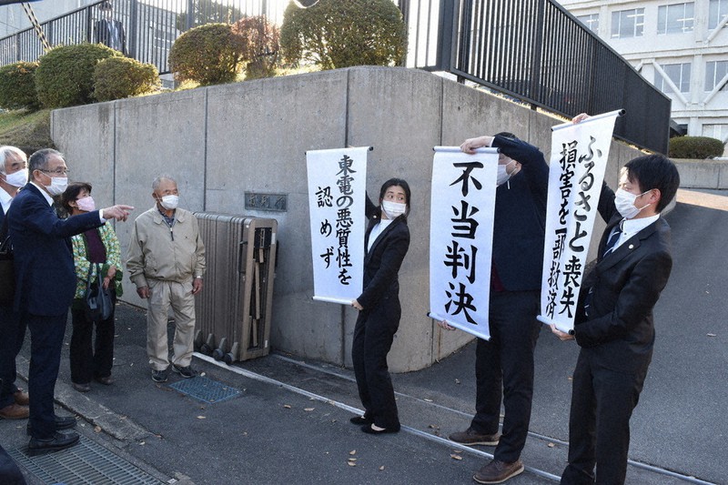 「不当判決」などと掲げた旗を見つめる関係者ら=福島県いわき市平の福島地裁いわき支部で2020年11月18日午後2時22分、柿沼秀行撮影