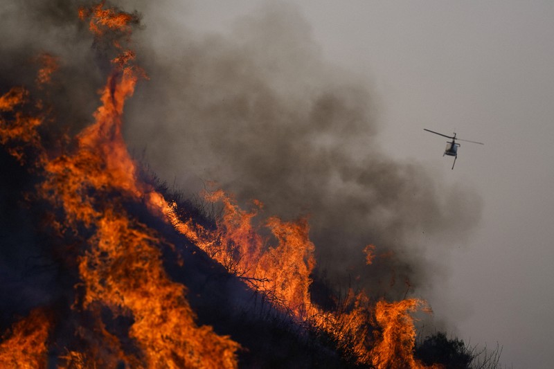 米カリフォルニア州で山火事の消火活動にあたる消防ヘリコプター=2020年10月27日、AP