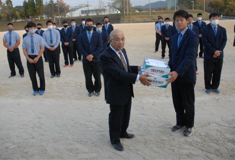 関商工高校ラグビー部の上野颯汰主将(手前右)にボール5個を渡す県毎日会の川村益美会長(同左)=岐阜県関市桐ケ丘1の同校で、花岡洋二撮影