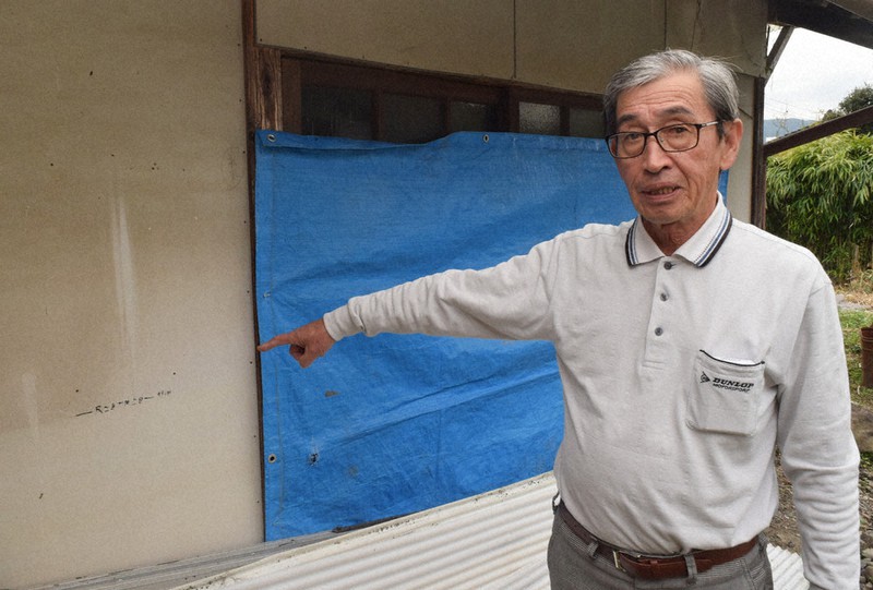 自宅前の物置小屋に残る浸水跡を指さしながら「ダムがあることで高齢者の命が救える」と話す城本雄二さん=熊本県人吉市で、吉川雄策撮影