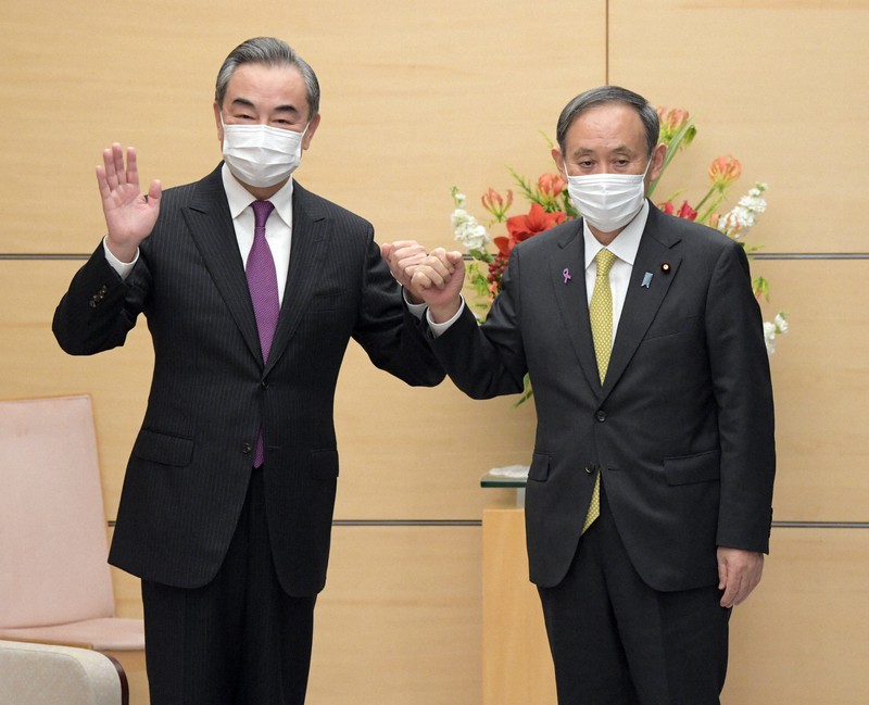 会談前に「グータッチ」をする菅義偉首相(右)と中国の王毅外相=首相官邸で2020年11月25日午後5時2分、竹内幹撮影