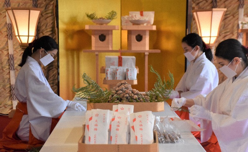 正月の縁起物「大福梅」の包装作業をする巫女たち=京都市上京区の北野天満宮で、添島香苗撮影
