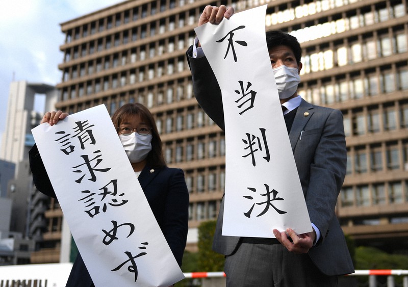判決後、「不当判決」などと書かれた紙を掲げる弁護士ら=大阪市北区で2020年11月30日午後2時3分、久保玲撮影