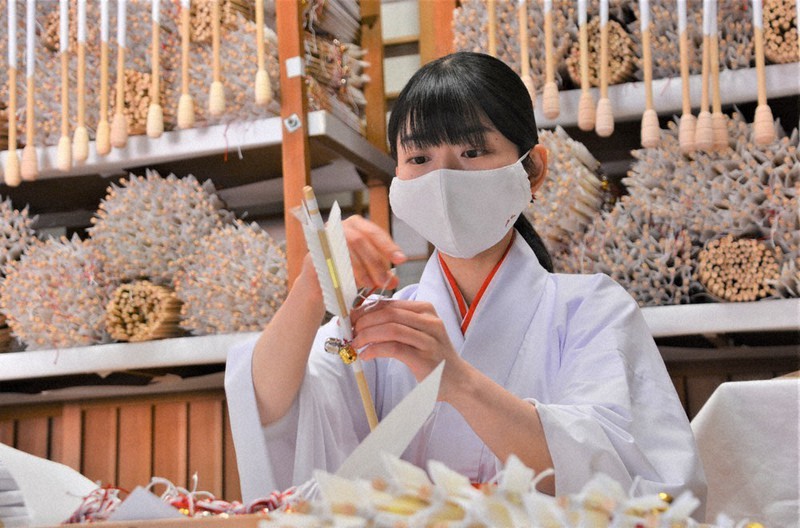 八幡宮オリジナルマスクを着けて破魔矢を製作するみこ=神奈川県鎌倉市の鶴岡八幡宮で2020年11月30日、因幡健悦撮影