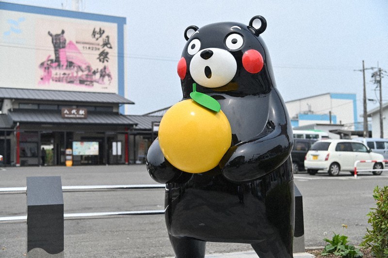 八代駅前で晩白柚を持つくまモン=熊本県八代市提供