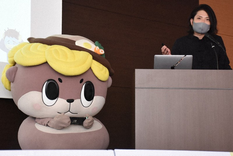 守時さんの講演中に携帯型ゲーム機で遊び始めるしんじょう君=高知市内で、郡悠介撮影