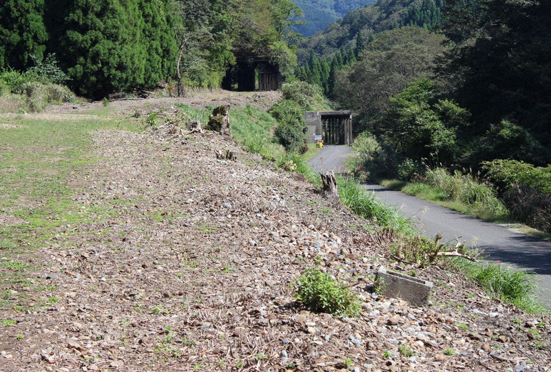 山中信号場のスイッチバック跡。右側の下っている舗装道路が旧北陸線の本線。左側の水平に伸びる砂利(バラスト)道は待避線。両方の奥の構造物がロックシェッド=福井県南越前町山中で=2020年10月2日午後0時17分、大島秀利撮影