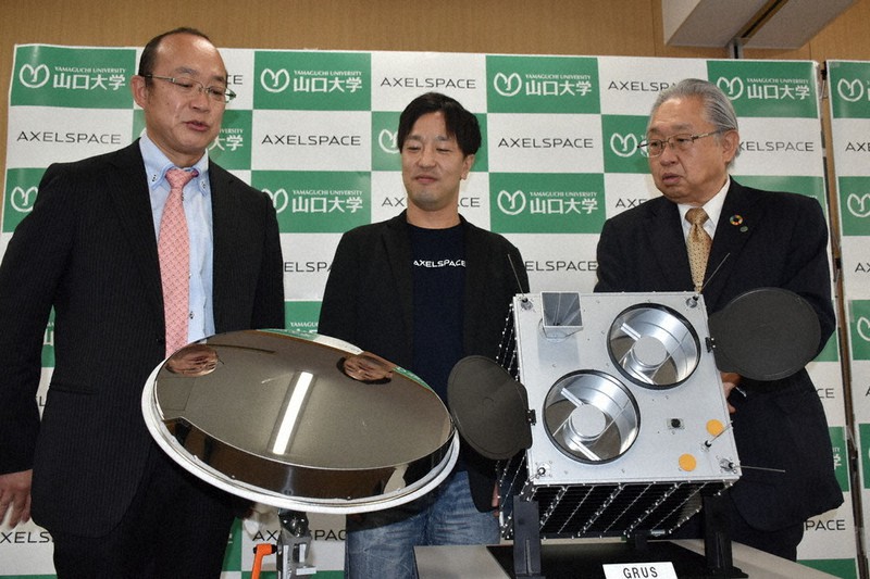 小型人工衛星(右)などを前に記者会見に臨む山口大とアクセルスペース社の担当者ら
