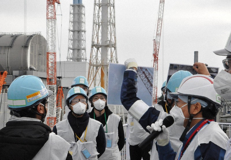 東京電力福島第1原発1~4号機を見渡せる高台で、東電の担当者の説明を聞く視察参加者ら=福島県大熊町の福島第1原発構内で2020年12月5日午後1時46分、高橋隆輔撮影