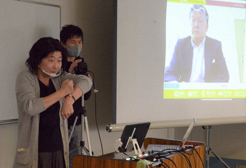 遠隔で診察を受ける患者役と手話のデモンストレーションをする石川県聴覚障害者協会のスタッフ(左)=金沢市内で2020年11月29日午後3時15分、阿部弘賢撮影