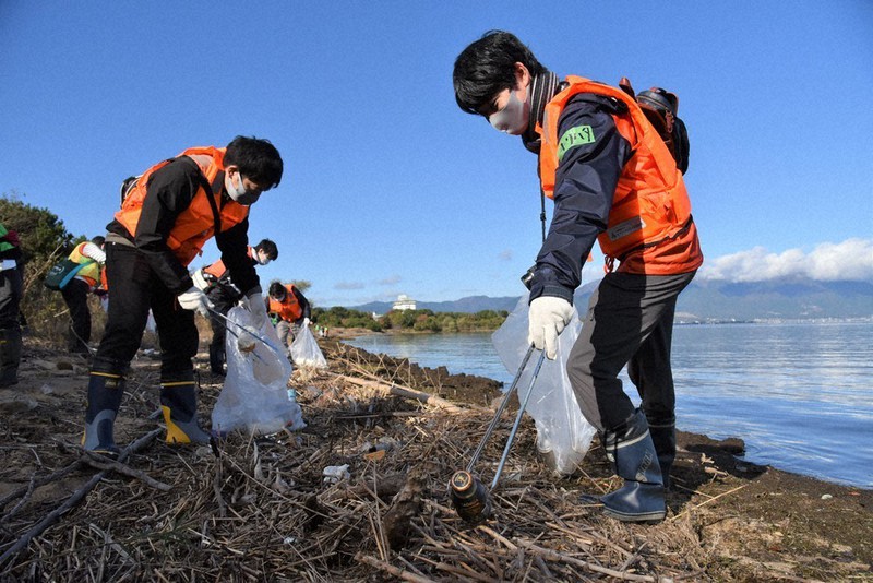 波打ち際に打ち上げられたゴミを拾う参加者。缶やプラスチック容器が目立った=滋賀県守山市今浜の琵琶湖岸で、安部拓輝撮影