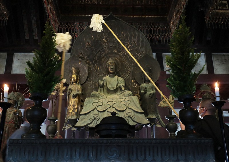 法隆寺金堂で、国宝の釈迦三尊像のほこりを払う僧侶=奈良県斑鳩町で2020年12月8日、小出洋平撮影
