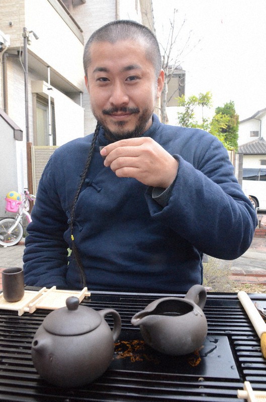 中国茶器で台湾産のウーロン茶を飲む弁髪姿の田淵雅圭さん=奈良県香芝市の自宅で、鶴見泰寿撮影