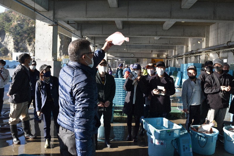 いわき市漁協の担当者(中央)から、生きのいい魚の見分け方などの説明を受ける東京山手調理師専門学校の生徒たち=福島県いわき市平沼ノ内の沼之内魚市場で