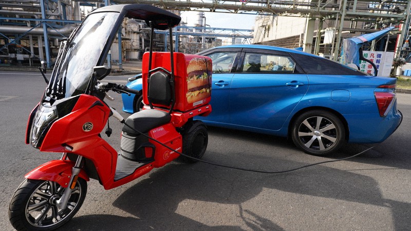 トヨタ自動車の燃料電池車「ミライ」から充電する日本マクドナルドの配達用電動バイク(手前)