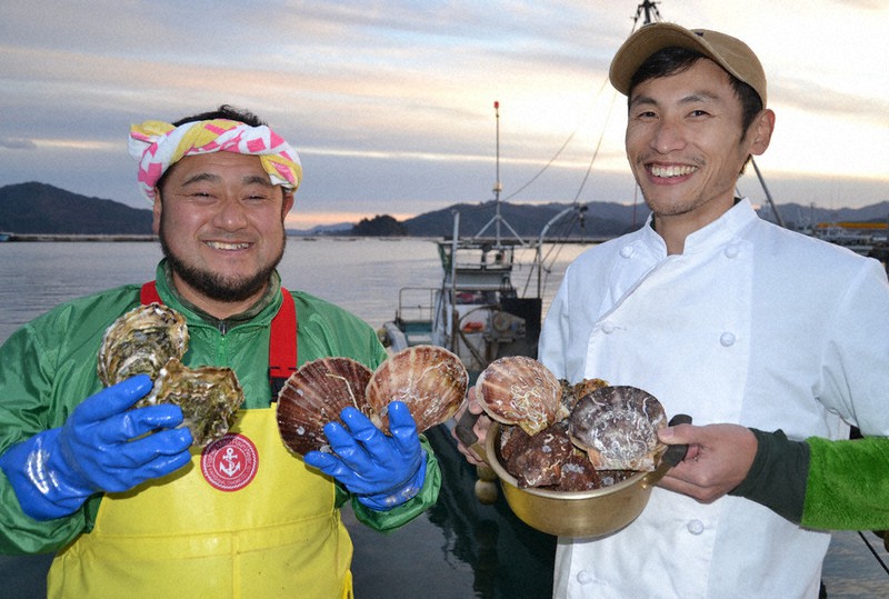 中村敏彦さん(左)の船の前で、取れたてのカキやホタテを手にする川村将崇さん=岩手県山田町大沢で2020年12月2日