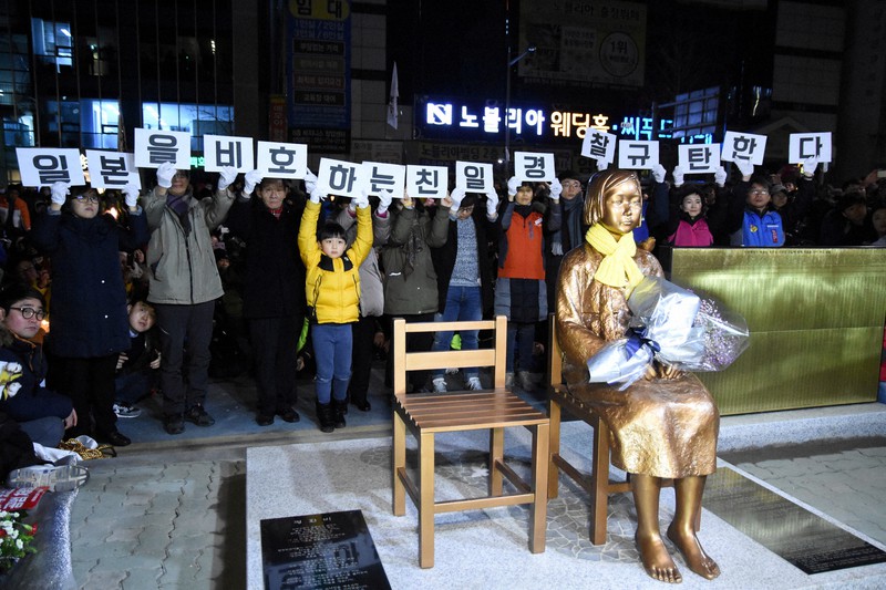 釜山の日本総領事館前に設置された少女像の除幕式。周辺は市民団体やメディア、警察でもみ合いとなった。プラカードのハングルは「日本をかばう親日警察を糾弾する」と書かれている=釜山市で2016年12月31日、大貫智子撮影