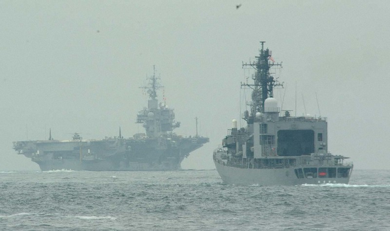 米海軍の空母キティホーク(左)の隊列の最後尾につき東京湾を出る護衛艦=2001年9月21日午後8時半、須賀川理撮影