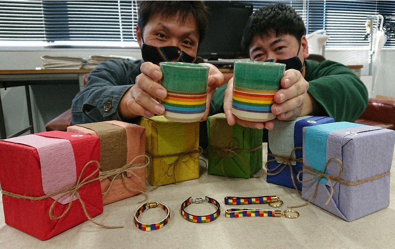 虹焼の湯飲み茶わんを手にする嶋田全宏さん(左)と加納克典さん。下は虹焼の6色のラッピングと虹紐=三重県伊賀市役所で、大西康裕撮影