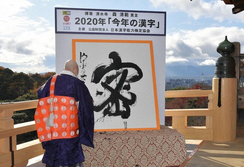 今年の漢字「密」を揮毫(きごう)する清水寺の森清範貫主。右奥は京都タワー=京都市東山区で14日(代表撮影)