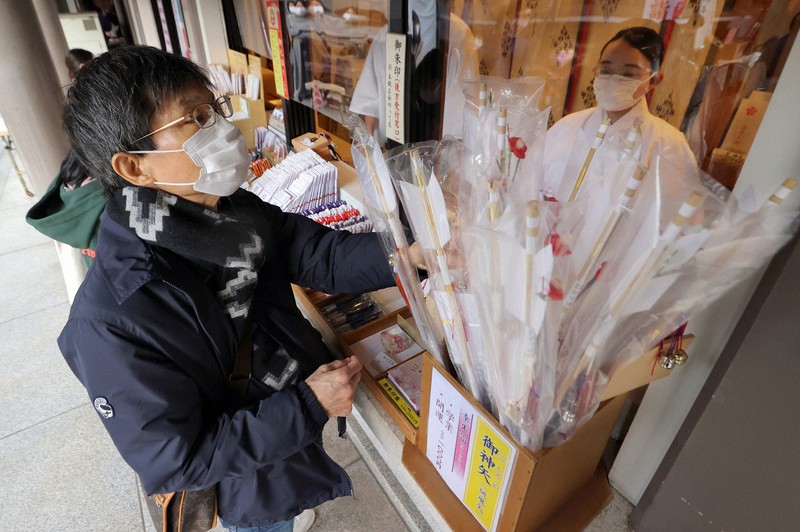 湯島天神の授与所に置かれた破魔矢を手にする参拝者=東京都文京区で2020年12月13日、喜屋武真之介撮影