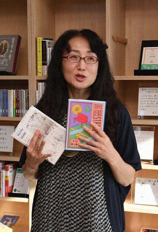 全米図書賞・翻訳文学部門に輝いた「JR上野駅公園口」の英訳版と日本版を持ち、笑顔で喜びを語る柳美里さん=南相馬市小高区東町のフルハウスで11月19日、高橋秀郎撮影