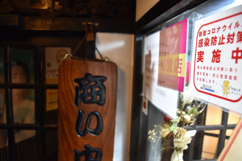 愛知県が「安全・安心宣言施設」に認定したPRステッカー(右端)を掲げる飲食店=名古屋市中区で2020年12月18日午後6時21分、酒井志帆撮影(画像の一部を加工しています)