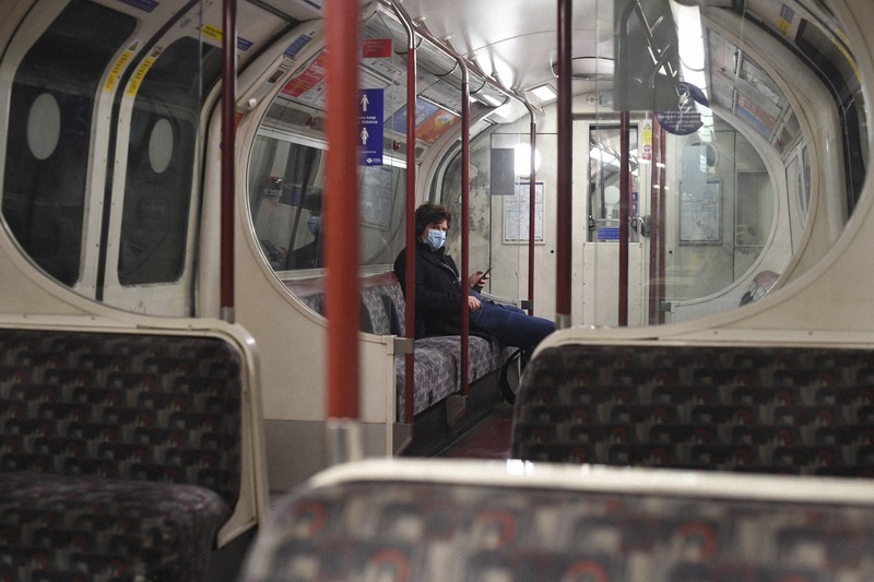 他の乗客がいない中、地下鉄の車両にぽつんと座っている男性=ロンドンで20日、AP