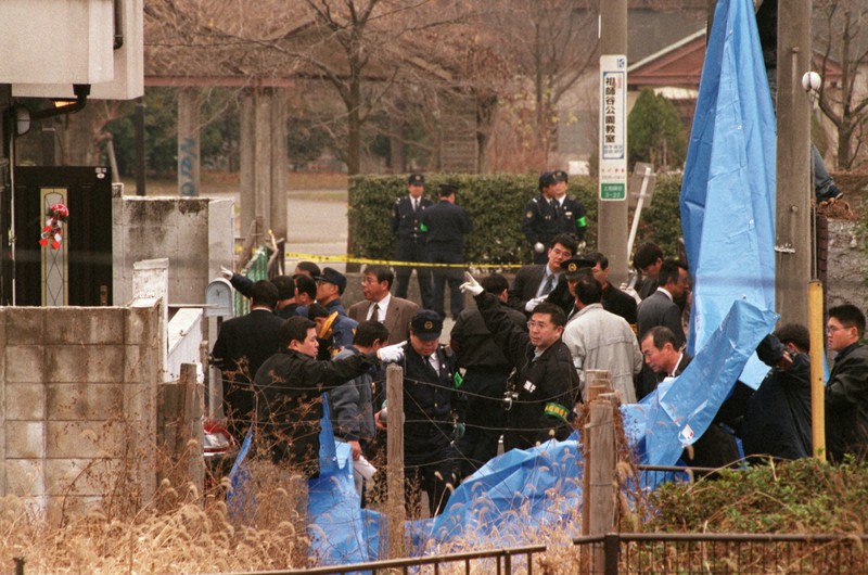 現場の宮沢さん方(左)周辺を調べる捜査員。犯人の血液からDNAが検出されている=東京都世田谷区上祖師谷で2000年12月31日、宮本明登撮影