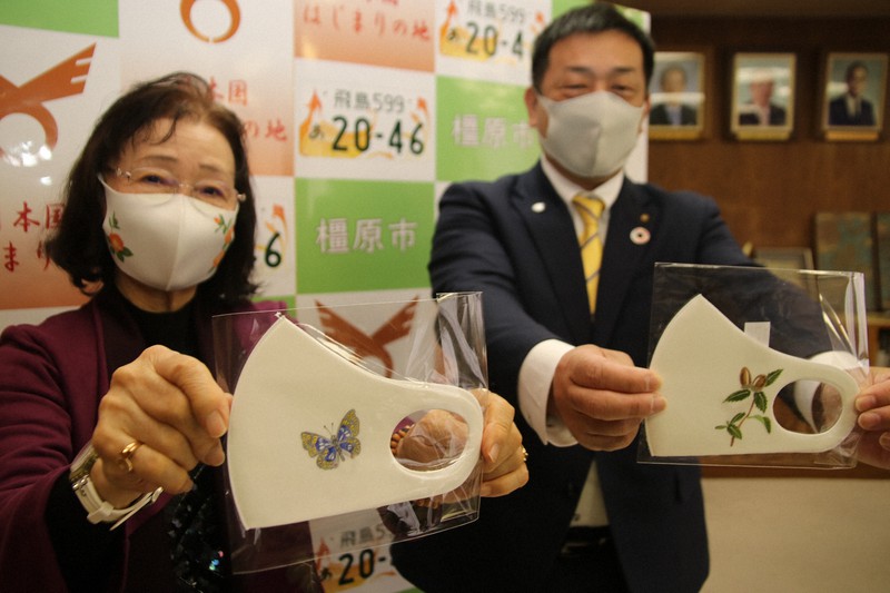 チョウなどの手描きの絵が入ったマスクを寄贈した日比肇子さん(左)=奈良県橿原市役所で2020年12月24日午後0時3分、姜弘修撮影