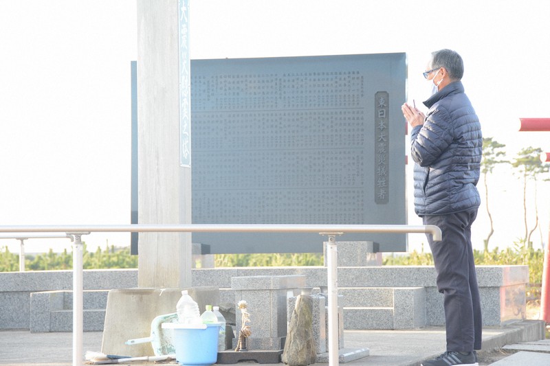 慰霊碑と慰霊塔の前で手を合わせる大学敏彦さん=仙台市若林区荒浜で2020年12月11日午前7時51分、深津誠撮影