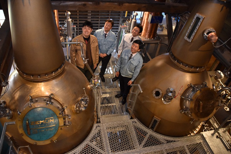 世界初の鋳物製ウイスキー蒸留器を眺める若鶴酒造の稲垣貴彦取締役(左)、老子製作所の元井秀治会長(右手前)ら=富山県砺波市の若鶴酒造で2020年11月12日午前11時7分、高良駿輔撮影