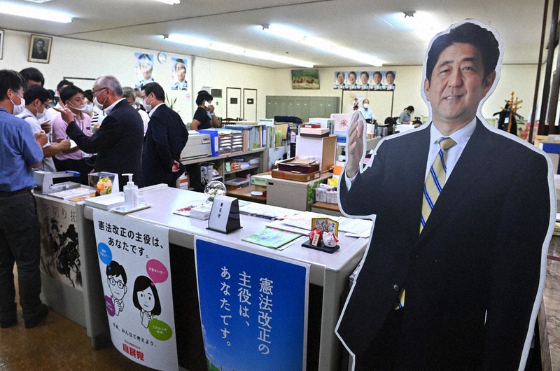 安倍首相(当時)の辞任表明を受け、報道陣に対応する事務所のスタッフ。事務所の入り口には安倍首相の等身大パネルが置かれていた=徳野仁子撮影