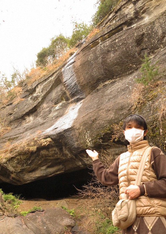 「鬼の岩屋」の前で大月桃太郎伝説を説明する大窪恭子さん=山梨県大月市で2020年12月14日、山本悟撮影