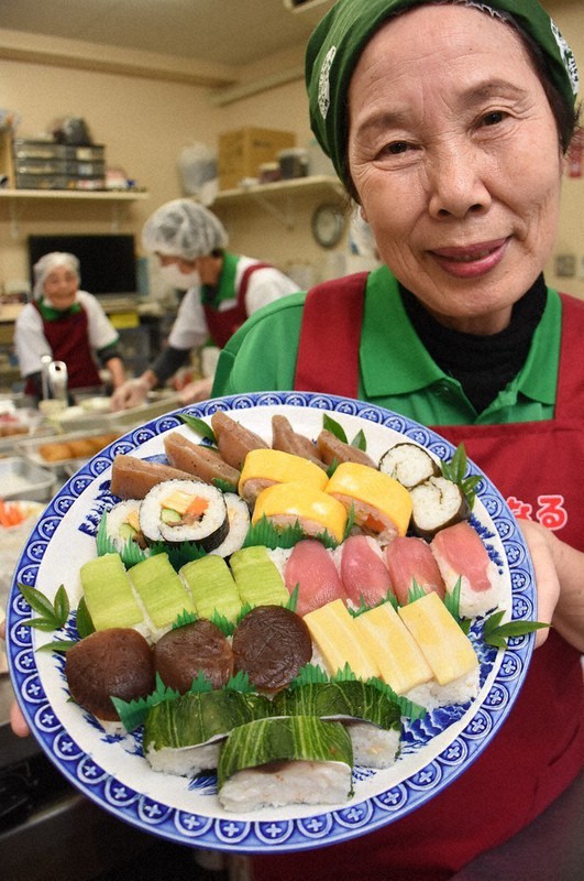 ミョウガやシイタケ、タケノコなどが乗った田舎ずしを手に笑顔の浜渦祥子さん=高知市で、郡悠介撮影