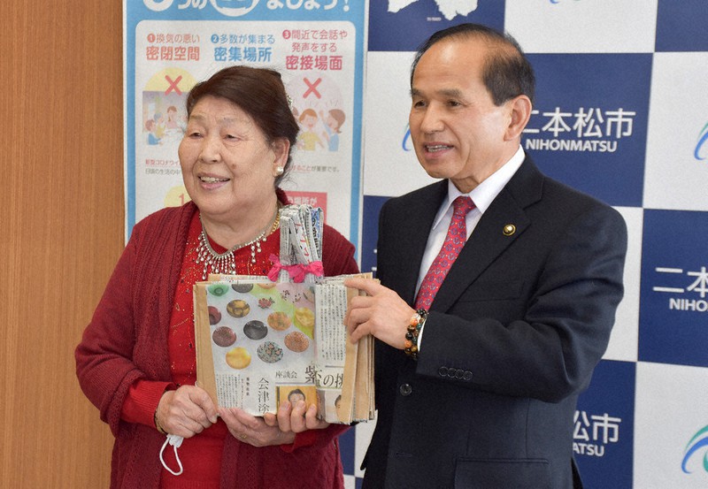 新聞紙などで作ったエコバッグを福島県二本松市の三保恵一市長(右)に手渡す菊地トミ子さん=同市役所で2021年1月8日、渡部直樹撮影