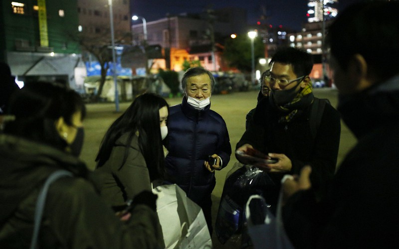 路上生活者に寝袋を配るため、支援者と打ち合わせをする石黒大圓さん(中央)=大阪市西成区で2020年12月18日、小出洋平撮影