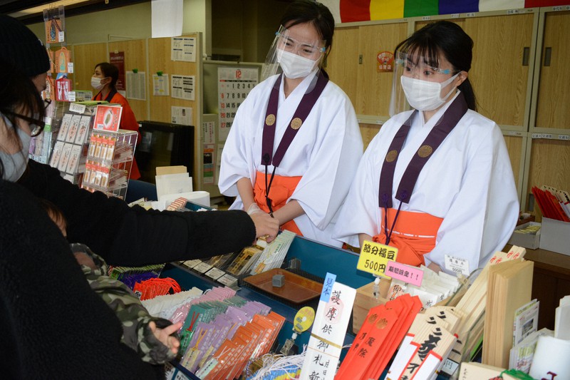 みこの衣装を着て、お守りなどを並べた台の後ろに立つANAグループの社員=千葉県成田市で2021年1月6日午後0時53分、中村宰和撮影