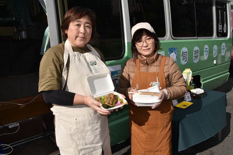 藤ノ木さんかく広場に止めたキッチンバスの前で弁当を披露する二岡美樹子さん(左)とスタッフの宇川友子さん=兵庫県川西市内で2020年12月15日午後0時34分、土居和弘撮影