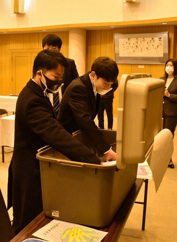 タイムカプセルを開ける新成人ら=青森県蓬田村ふるさと総合センターで2021年1月10日、南迫弘理撮影