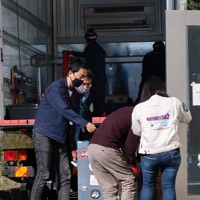 相模原市のJAXA宇宙科学研究所に到着した、探査機はやぶさ2のカプセルが入ったコンテナを施設に運び入れるサンプラーチームのメンバー＝JAXA相模原キャンパスで2020年12月8日、永山悦子撮影