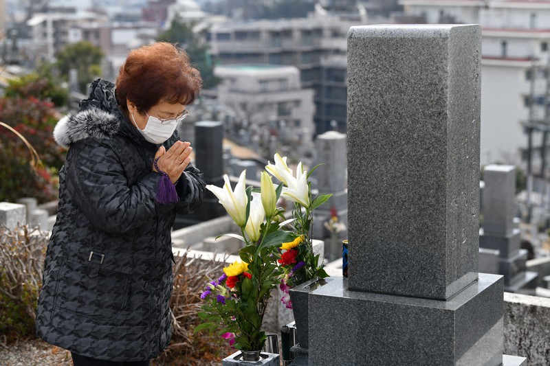 長男基弘さんの墓前に手を合わせる競恵美子さん=名古屋市天白区で2021年1月16日午前10時49分、兵藤公治撮影