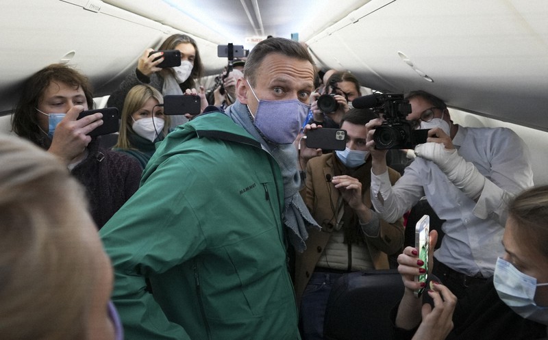 ドイツからロシアに向かう飛行機の中で報道陣に囲まれるナワリヌイ氏(中央)=2021年1月17日、AP