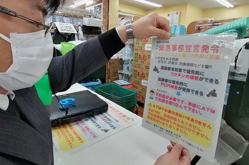 「ワクチン接種」などをかたった不審電話への注意を呼びかけるチラシを張る滝野川署員=東京都北区で