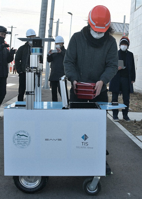 搬送ロボットが配達した弁当を受け取る関係者=福島県南相馬市原町区の福島ロボットテストフィールドで2021年1月15日、高橋秀郎撮影