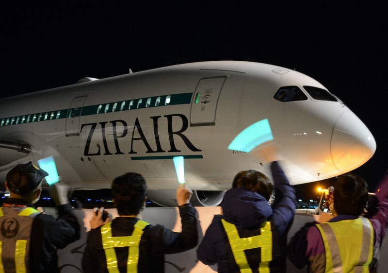 出発するホノルル線の初便に手を振る「ZIPAIR Tokyo」のスタッフら=成田空港で2020年12月19日午後8時9分、中村宰和撮影