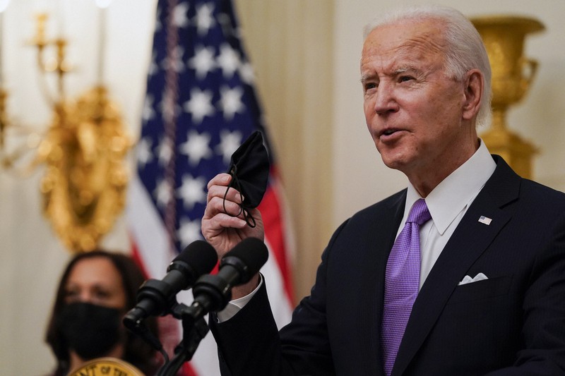 黒いマスクを手に新型コロナウイルス対策について話すバイデン米大統領=ワシントンのホワイトハウスで2021年1月21日、AP