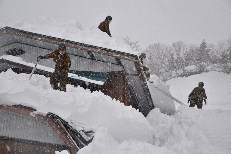積雪で壊れた屋根の部分に注意を払いながら雪下ろしをする自衛隊員=秋田県湯沢市で2021年1月7日午後1時32分、高野裕士撮影
