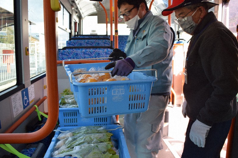 路線バスで乗客と一緒に農産物を運ぶ「貨客混載」の実証実験が始まり、コンテナいっぱいの青果を積み込む生産者とJAの職員=兵庫県三田市下里で2021年1月19日午前10時35分、稲田佳代撮影
