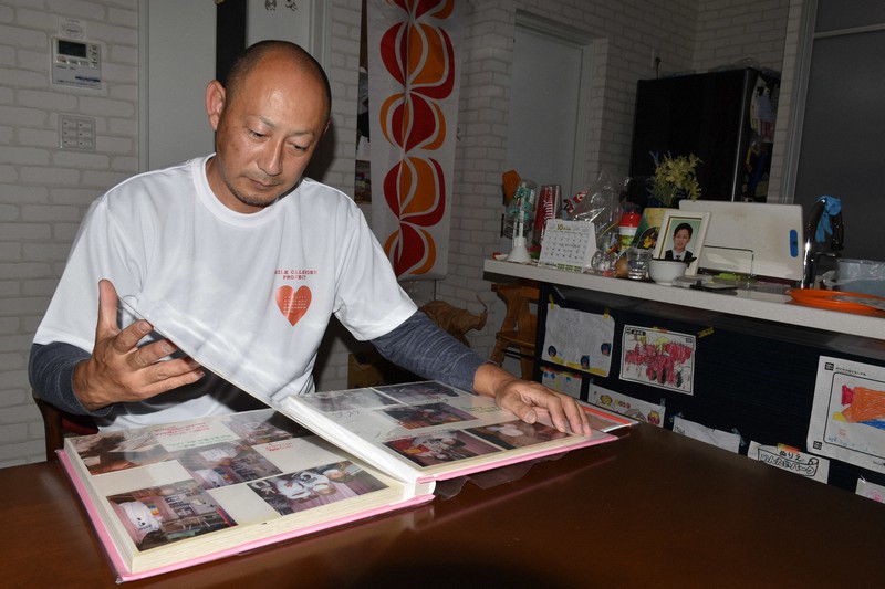 長男竜一さんのアルバムを見る寺際伸一さん=津市美川町で2020年10月27日午後11時42分、谷口豪撮影